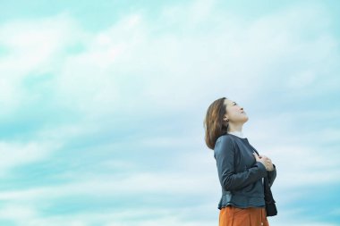 Sıradan giyinmiş Asyalı iş kadını gökyüzüne bakıyor.