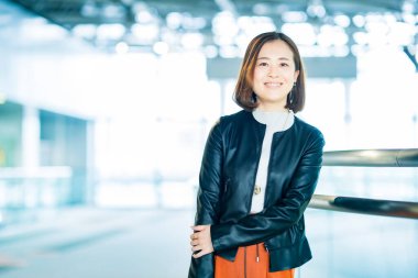 Ofis binasında sıradan giyinmiş Asyalı bir iş kadını.