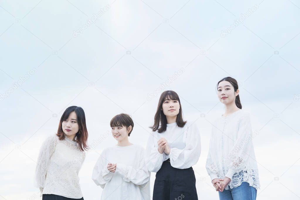 4 Japanese women wearing white tops and talking with a smile 