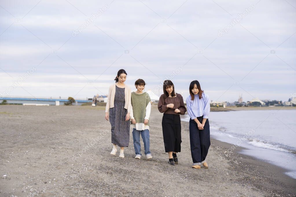 Four young women walking along the sea in the dusk