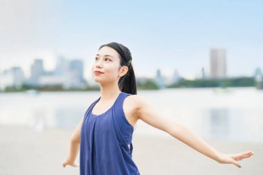 Genç bir kadın şehrin sahillerinde esniyor ve derin bir nefes alıyor.