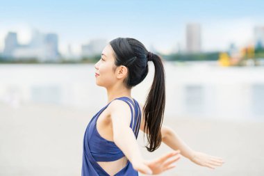 Genç bir kadın şehrin sahillerinde esniyor ve derin bir nefes alıyor.