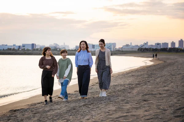 Four young women walking along the sea in the dusk