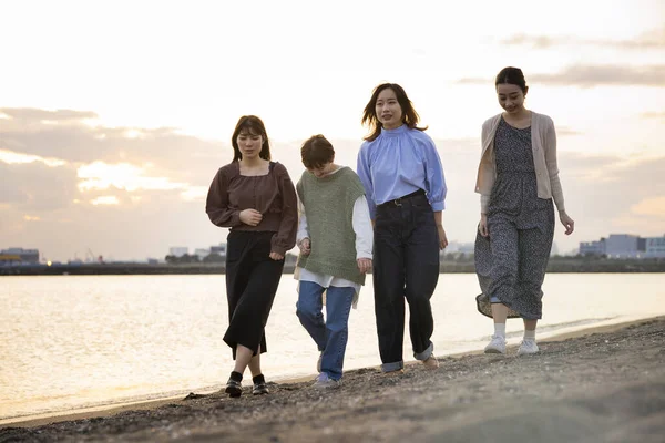 夕暮れ時に4人の若い女性が海を歩いている — ストック写真