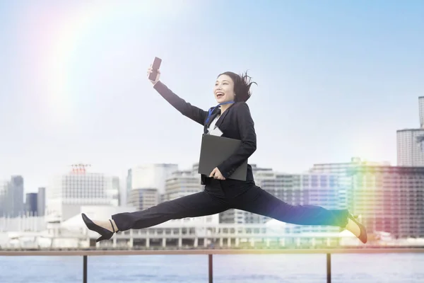 A young business woman in a suit jumping with a smile