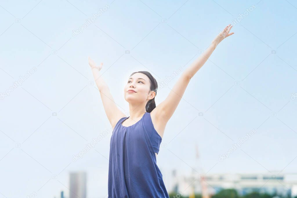 Young woman stretching and taking a deep breath on the beach of the city