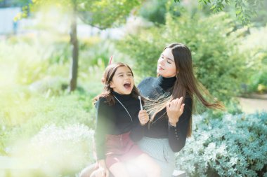 Anne ve kızı dışarıda gülümseyerek dişlerini fırçalıyorlar.