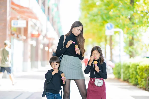 Mom and two kids eating ice cream with smile outdoors