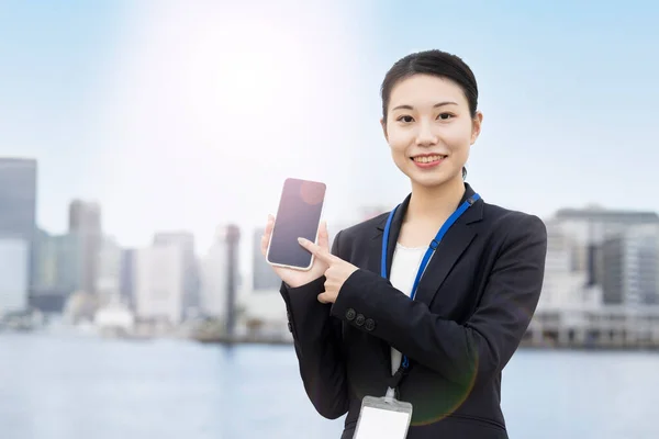 アジアの若いビジネス女性が笑顔でスマートフォンを操作し — ストック写真