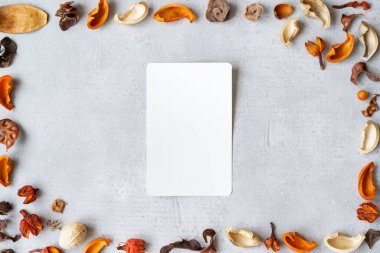 Beton bir düzleme yerleştirilmiş beyaz kağıt ve kurumuş bitkiler.