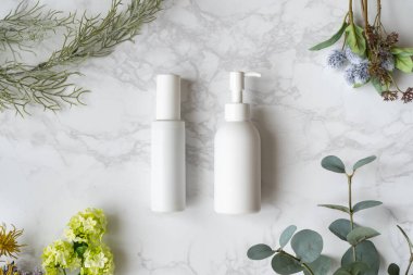 Mermer bir tabağa yerleştirilmiş beyaz şişe ve yeşil dekor.