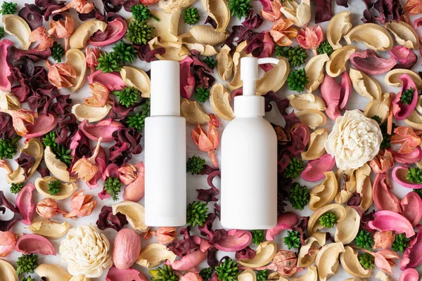 Zwei Weiße Flaschen Auf Getrockneten Blumen Verteilt — Stockfoto