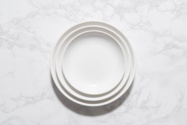 Mermer bir tabağa yerleştirilmiş boş beyaz bir tabağın kuş bakışı görüntüsü.