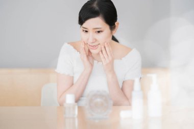 Asyalı kadın odada tenine dokunup kontrol ediyor.