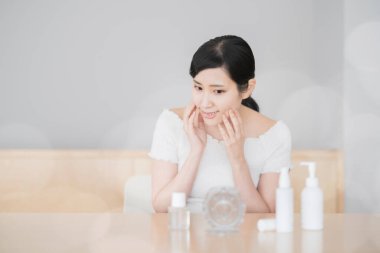 Asyalı kadın odada tenine dokunup kontrol ediyor.