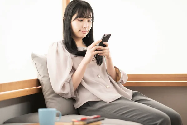 Asiatin Sitzt Hause Und Bedient Ein Smartphone — Stockfoto