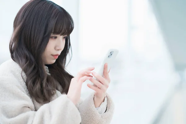 Asian young woman watching the screen and operating a smartphone