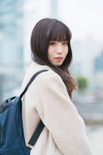 Молодая азиатка выходит с рюкзаком на спине