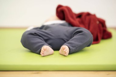 Asyalı erkek bebek, paspasın üstünde rahat bir şekilde uyuyor.