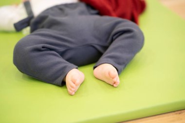 Asyalı erkek bebek, paspasın üstünde rahat bir şekilde uyuyor.