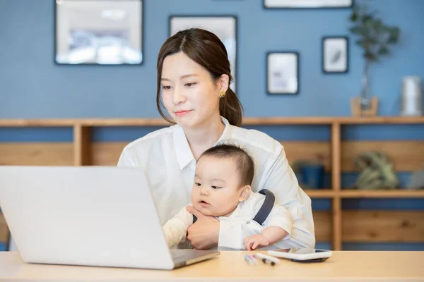 Asijské Žena Držení Dítě Provoz Notebook Indoors — Stock fotografie