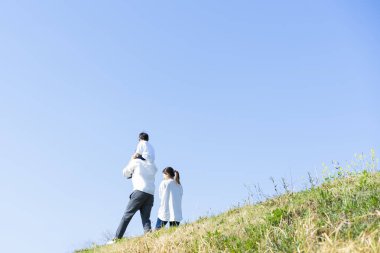 Aileler ve çocuklar mavi gökyüzünün altında gülümseyerek yürüyorlar.