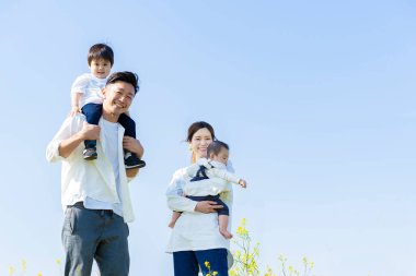 Aileler ve çocuklar mavi gökyüzünün altında gülümseyerek yürüyorlar.