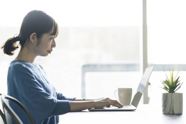 Odadaki masada dizüstü bilgisayar kullanan bir kadın.