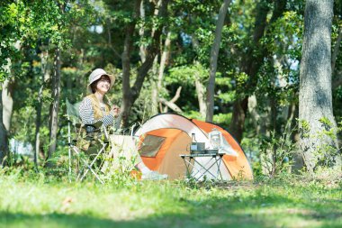 Solo kamp görüntüsü - çadırın önünde dinlenen genç bir kadın