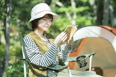 Tek kişilik kamp imajı. Kitap okuyan genç bir kadın.