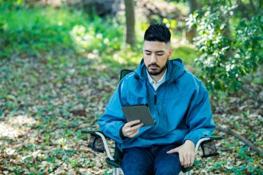 Solo kamp resmi - Tablet aygıtının ekranına bakan bir adam 