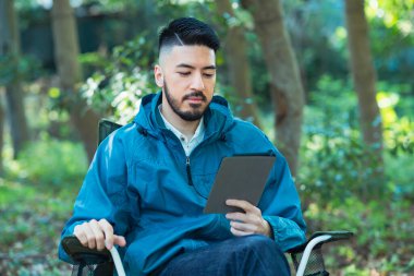 Solo kamp resmi - Tablet aygıtının ekranına bakan bir adam 