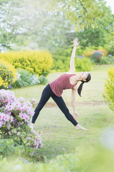 Young woman doing yoga in a green park on fine day