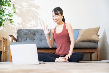 Yoga hocası odada bilgisayar ekranına konuşuyor.