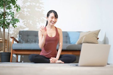 Yoga hocası odada bilgisayar ekranına konuşuyor.