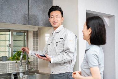 İş elbiseli bir adam mutfakta bir kadına açıklama yapıyor.) 