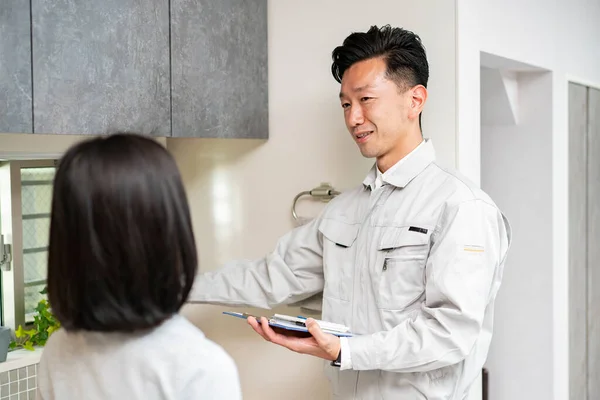 Een Man Werkkleding Legt Uit Aan Een Vrouw Keuken Waterleverancier — Stockfoto