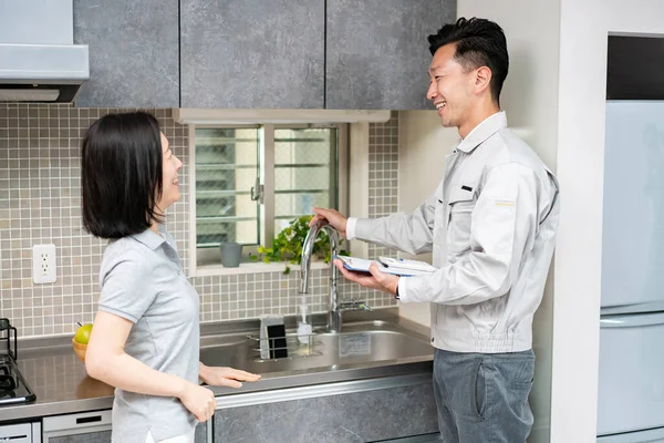 Een Man Werkkleding Legt Uit Aan Een Vrouw Keuken Waterleverancier — Stockfoto