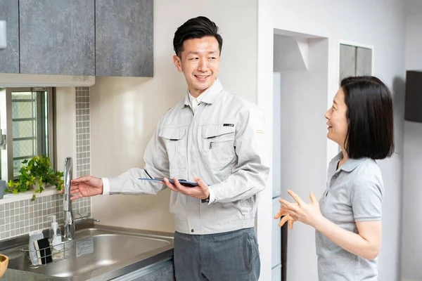 Een Man Werkkleding Legt Uit Aan Een Vrouw Keuken Waterleverancier — Stockfoto