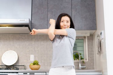 Asyalı orta yaşlı kadın odasında hafif egzersiz yapıyor. 