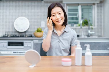 Asyalı orta yaşlı kadın evde cilt durumunu kontrol ediyor.