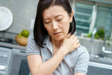 Odasında yorgun görünen Asyalı orta yaşlı bir kadın.