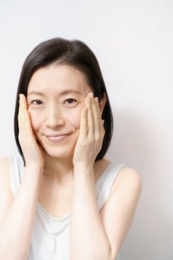 Asyalı kadınlar yüzlerine dokunuyor (40 'lı veya 50' li yaşlarda)) 