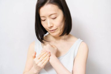 Bir kadın elinin arkasına krem sürüyor. 