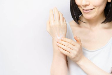 Bir kadın elinin arkasına krem sürüyor. 