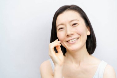 Asyalı kadınlar yüzlerine dokunuyor (40 'lı veya 50' li yaşlarda)) 