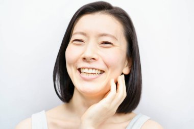 Asyalı kadınlar yüzlerine dokunuyor (40 'lı veya 50' li yaşlarda)) 