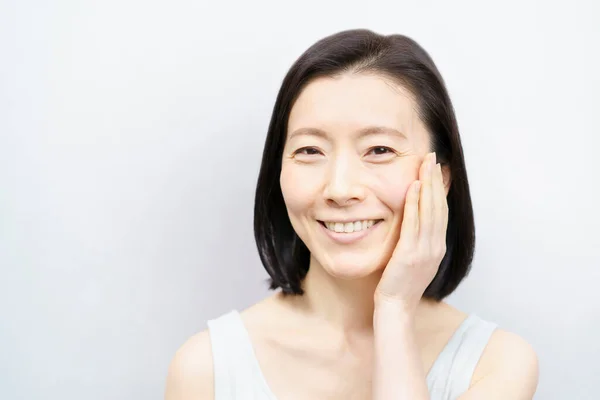 顔に触れるアジア系女性 50代 — ストック写真