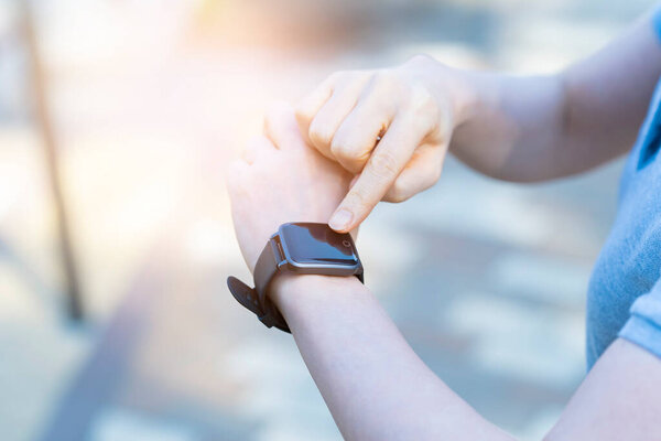 Азиатская женщина среднего возраста, управляющая умными часами на открытом воздухе