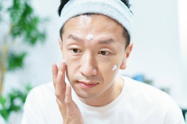 Erkekler odada yüzlerine nemlendirici krem sürüyor.